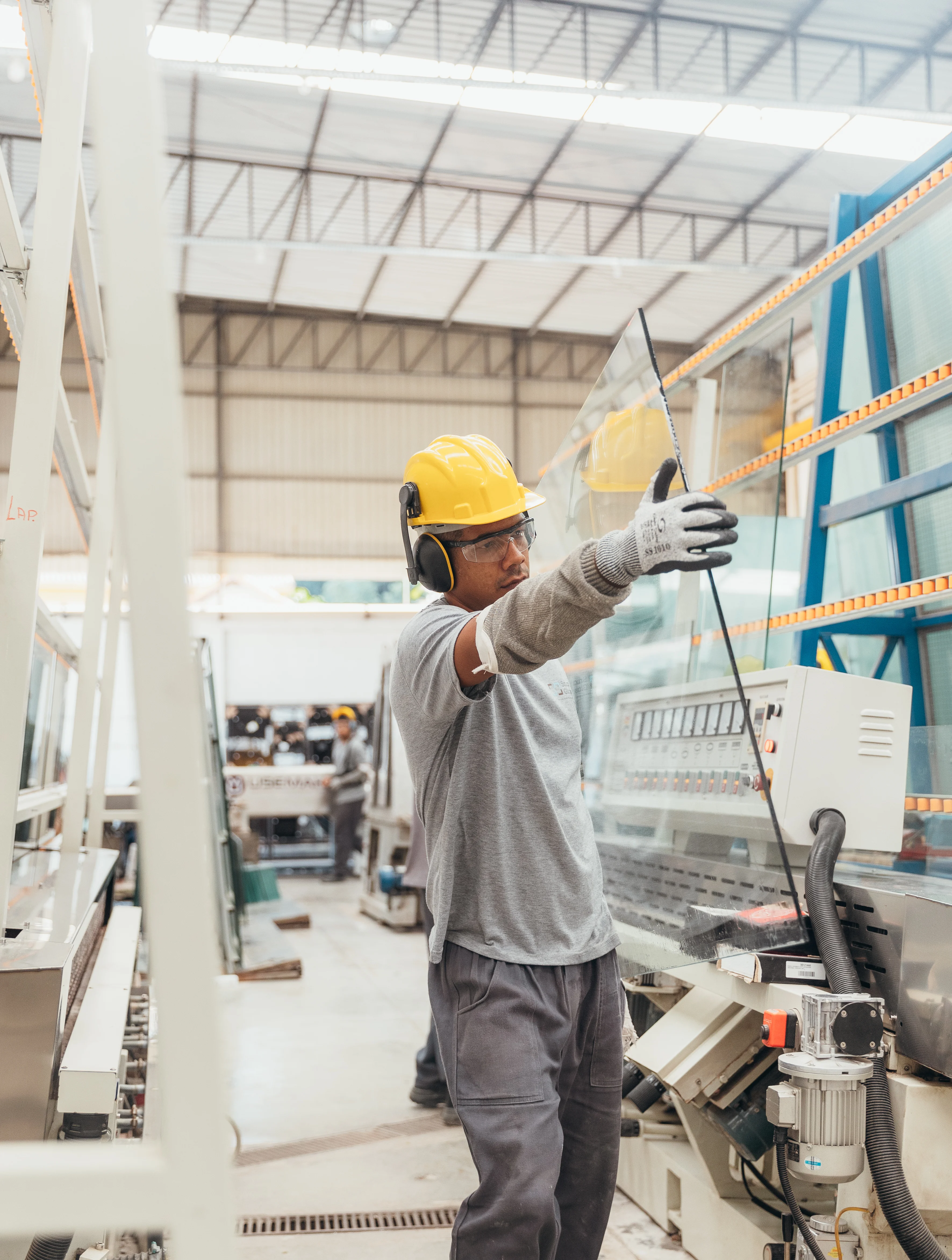 A technician handling a processed glass panel on the production line